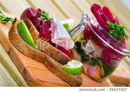 Marinated poutassou served at bread with beets, onions and marinade from lime juice 56625997