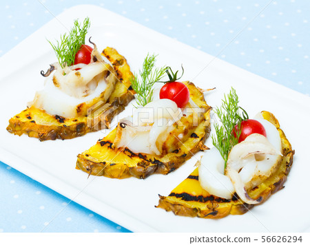 Sepia fried on a grill with pineapple and cherry tomatoes is tasty dish 56626294