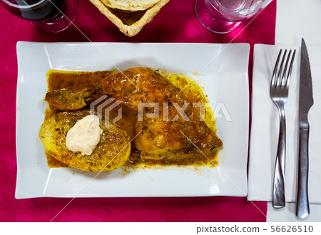 Tasty baked chicken in sauces with potatoes at plate, nobody 56626510