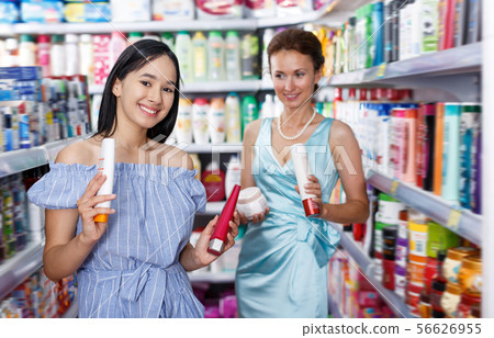 Cheery woman and girl looking haircare products Cheery woman and girl looking haircare products 56626955