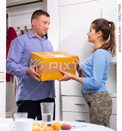 Man courier with box is delivering order for young woman Man courier with box is delivering order for young woman 56627409