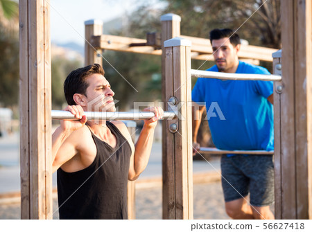 Smiling adult men are doing pull-ups Smiling adult men are doing pull-ups 56627418