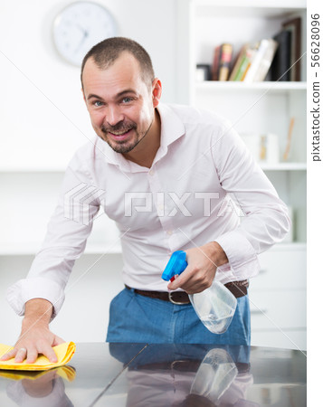 Positive young man cleaning office desk Positive young man cleaning office desk 56628096