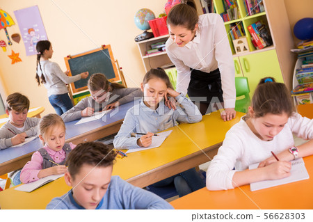 Woman teacher helping to children with work at lesson 56628303