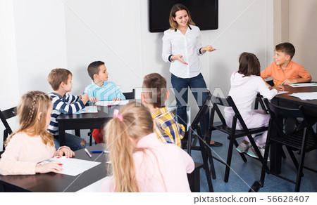Little children with cheerful teacher drawing in classroom 56628407