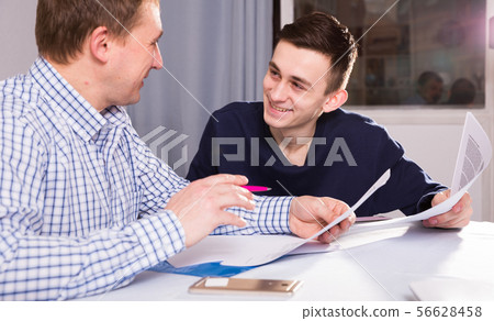 Man with his adult son are reading documents together Man with his adult son are reading documents together 56628458