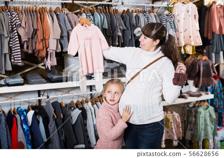Pregnant woman examining baby's clothes 56628656