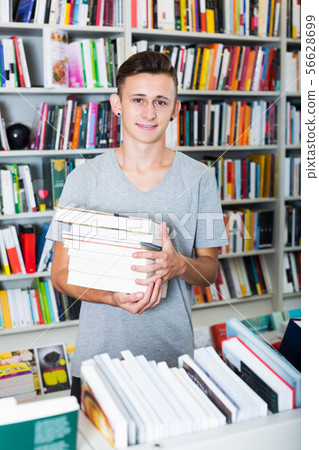 Teenager holding pile of books Teenager holding pile of books 56628699