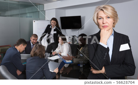 Upset mature businesswoman standing in meeting room Upset mature businesswoman standing in meeting room 56628704