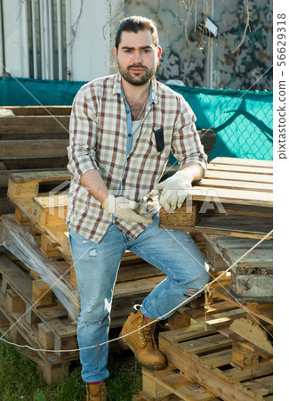 Man repairs wooden pallets in the backyard of a country house 56629318