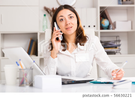 Adult woman working with laptop and talking by smartphone 56630221