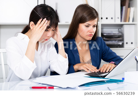 Women reading documents with upset faces at office Women reading documents with upset faces at office 56630239