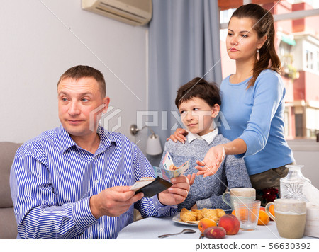 Upset father giving money to wife and son 56630392