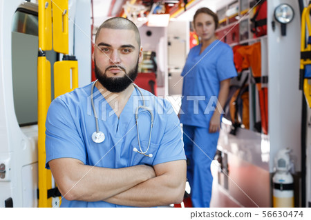 Portrait of serious male and female paramedicals near ambulance car 56630474