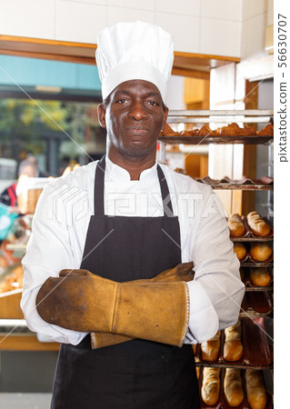 Confident baker in uniform and heat resistant gloves Confident baker in uniform and heat resistant gloves 56630707