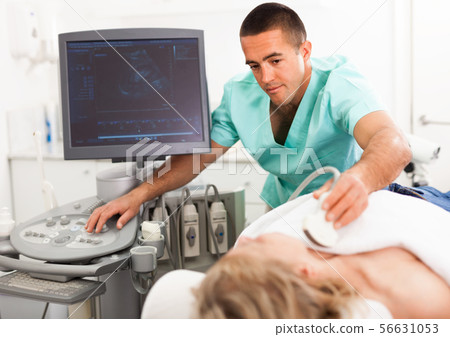 Young man sonographer using ultrasonography machine checking female patient in hospital diagnostic room 56631053