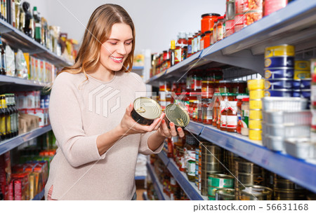 Woman customer holding canned fish goods in the food store 56631168