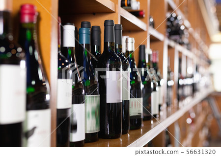 Rows of wine bottles on shelves in modern wine store waiting for customers Rows of wine bottles on shelves in modern wine store waiting for customers 56631320