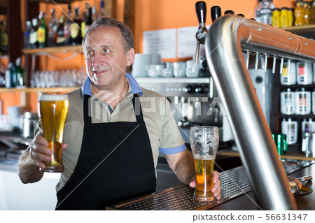 Smiling barman is offering unbottled beer to next client Smiling barman is offering unbottled beer to next client 56631347