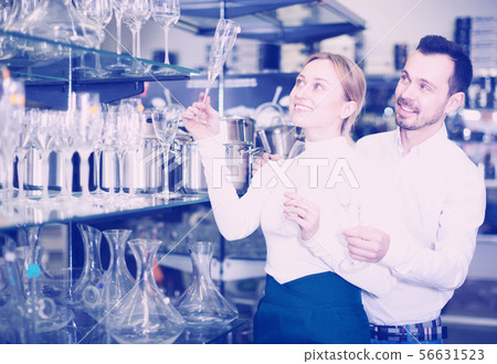 Couple choosing glasses in store Couple choosing glasses in store 56631523