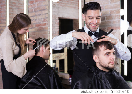 Male hairdresser cutting hair of male client 56631648