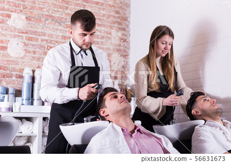 Men relaxing while hairdressers washing their hair 56631673
