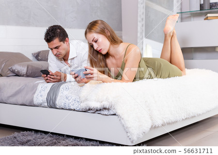 Bored couple with phones on bed 56631711