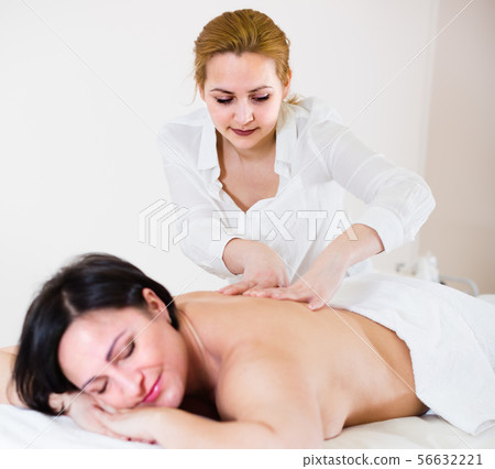 Happy woman likes work of young masseur 56632221