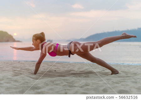 Young woman in swimsuit exercising on beach stretching her legs during sunset at sea. Fitness girl Young woman in swimsuit exercising on beach stretching her legs during sunset at sea. Fitness girl 56632516