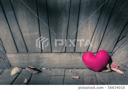 A little red heart pillow on old chair in garden. 56634010