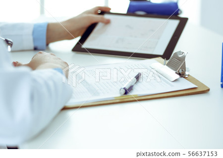 Doctor working table. Woman physician using tablet computer while sitting in hospital office close 56637153