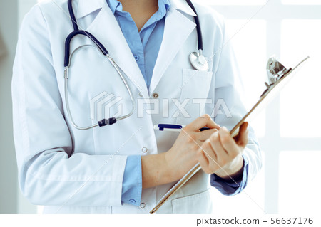 Female doctor using medical form on clipboard closeup. Physicianat work in hospital or clinic Female doctor using medical form on clipboard closeup. Physicianat work in hospital or clinic 56637176