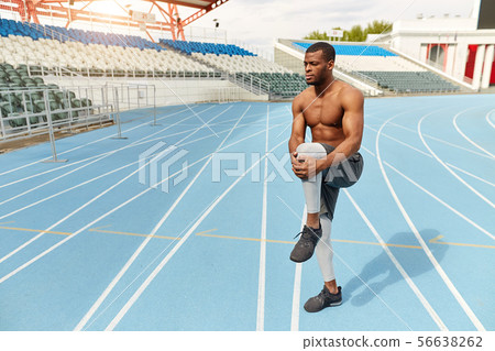 motivated strong runner stretching leg in the stadium 56638262