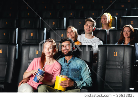 Cheerful good looking company enjoying premiere and eating popcorn. Cheerful good looking company enjoying premiere and eating popcorn. 56638823