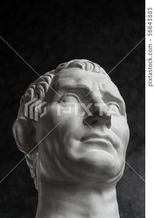 Gypsum copy of ancient statue Augustus head on dark textured background. Plaster sculpture man face. Gypsum copy of ancient statue Augustus head on dark textured background. Plaster sculpture man face. 56643885