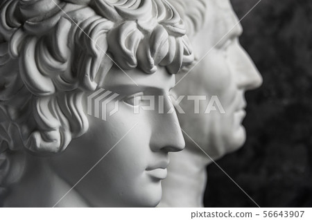 Gypsum copy of ancient statue Augustus and Antinous head on dark textured background. Plaster Gypsum copy of ancient statue Augustus and Antinous head on dark textured background. Plaster 56643907