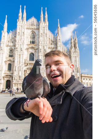 Travel, holidays and winter vacations concept - Happy man take selfie photo with funny pigeons in 56645686