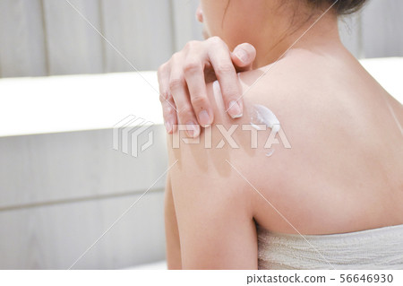 The woman is applying cream,lotion on her back., 56646930