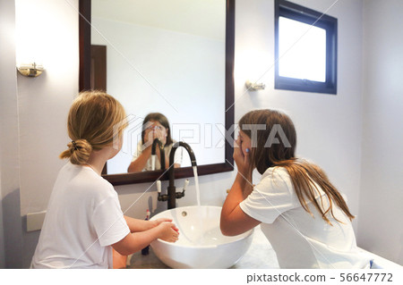Happy children girls are washing their faces in a 56647772