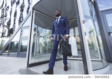 Confident Afro Businessman With Briefcase Leaving Modern Office Building 56648868