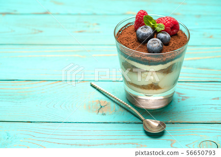 Classic tiramisu dessert with blueberries and strawberries in a glass cup on wooden background 56650793
