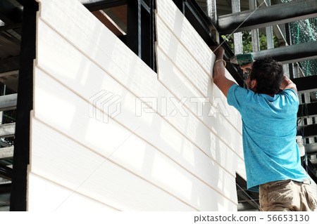 man shoot screw smart wood panel to house frame man shoot screw smart wood panel to house frame 56653130