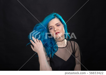 Style and fashion concept - Young and attractive woman with blue hair posing over black background 56653422
