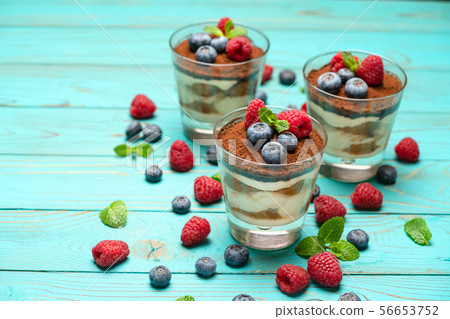 Classic tiramisu dessert with blueberries and strawberries in a glass cup on wooden background Classic tiramisu dessert with blueberries and strawberries in a glass cup on wooden background 56653752