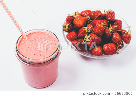 Strawberry smoothie in glass next to bowl Strawberry smoothie in glass next to bowl 56653805