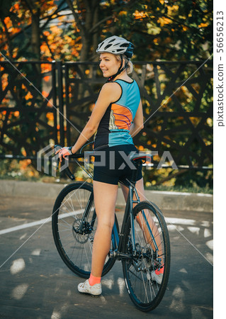 Photo on side of young woman in helmet on bike ride on summer day Photo on side of young woman in helmet on bike ride on summer day 56656213