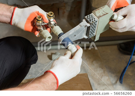 The worker is soldering the heating system pipes. The worker is soldering the heating system pipes. 56656260