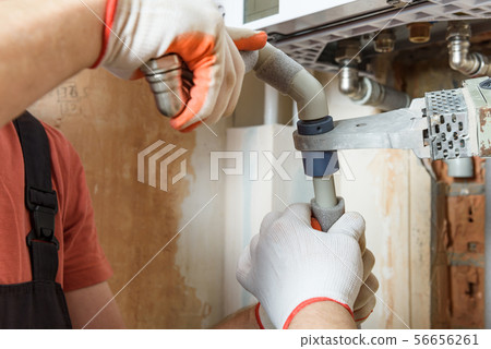 The workers is soldering the gas boiler pipes. The workers is soldering the gas boiler pipes. 56656261