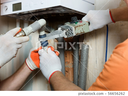 The workers is soldering the gas boiler pipes. The workers is soldering the gas boiler pipes. 56656262