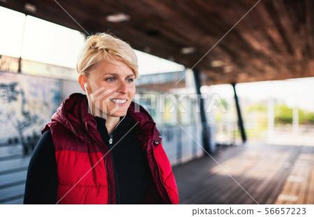 A portrait of young sportswoman doing exercise outdoors, resting. A portrait of young sportswoman doing exercise outdoors, resting. 56657223
